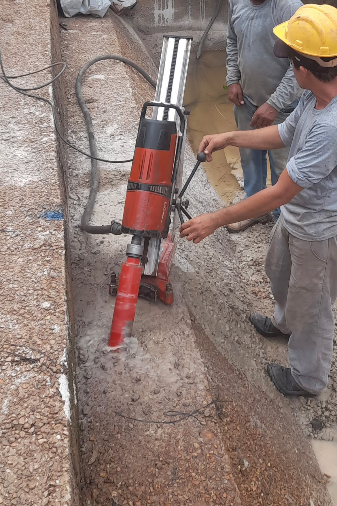 Equipe operando equipamento de perfuração em concreto armado